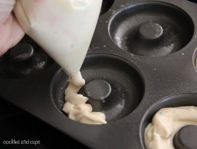 Funfetti cake batter being piped into a donut pan