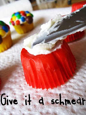 Frosting being spread on an inverted red muffin cup