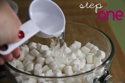 Water is added into a mixing bowl filled with marshmallows.