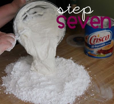 A mixture of melted marshmallow and powdered sugar is poured over top a pile of powdered sugar.