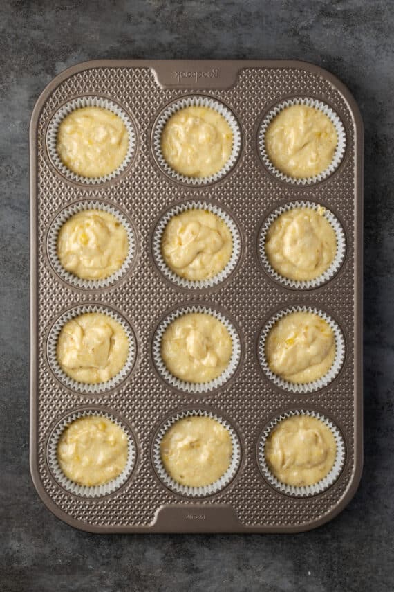 A lined 12-well cupcake tin filled with banana cupcake batter