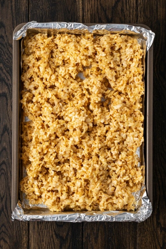 Rice krispie treat mixture added to a 9x13 baking pan lined with foil.