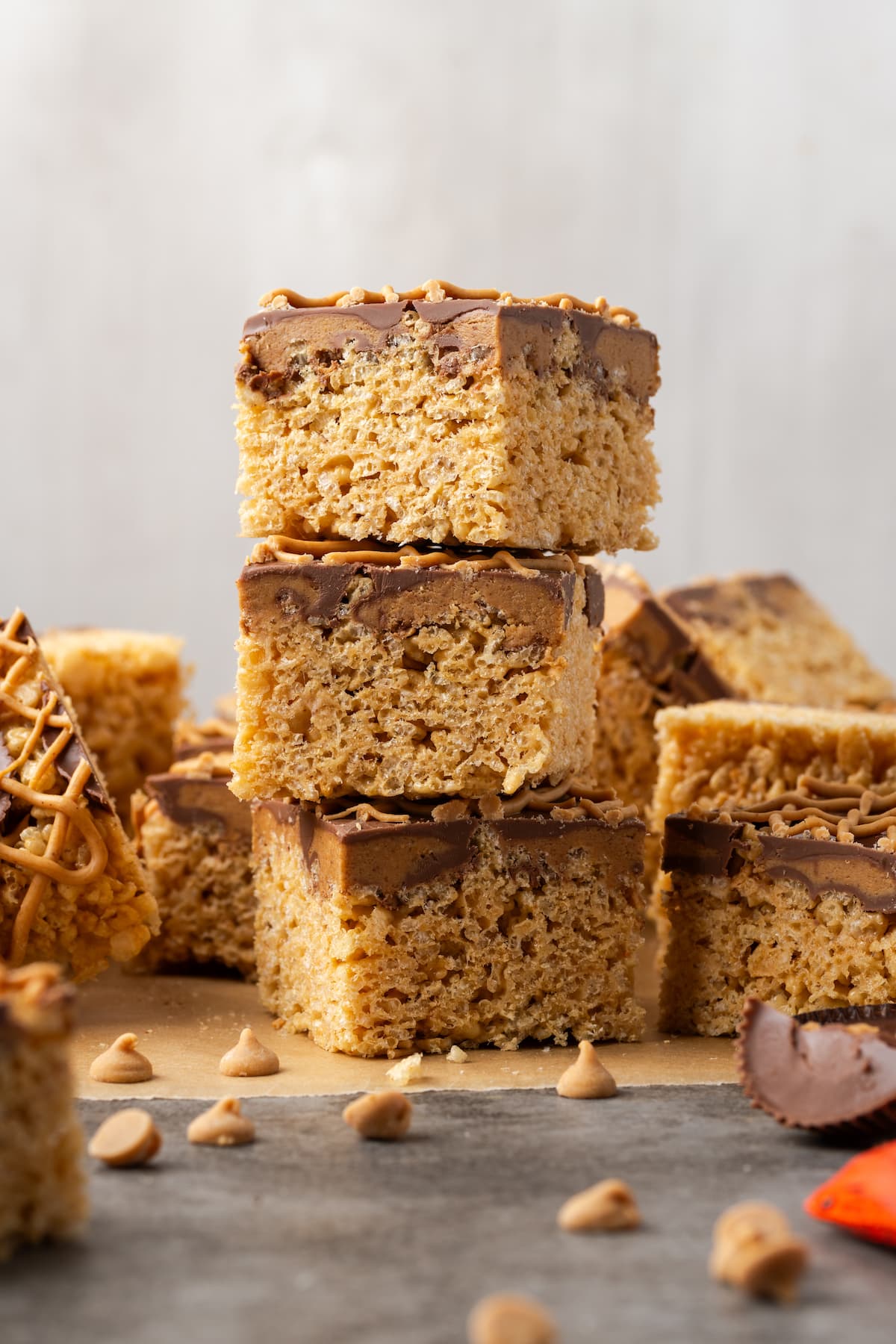 A stack of three peanut butter rice krispie treats on a countertop with more krispie treats in the background.