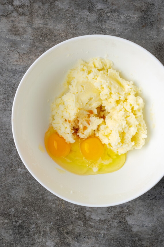 Two eggs cracked in a bowl of butter and sugar.