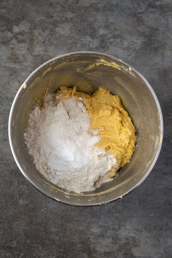 Dry ingredients added to wet cookie dough ingredients in a metal bowl.