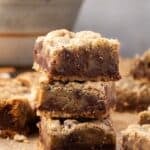 Three chocolate toffee bars stacked with more bars in the background.