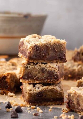 Three chocolate toffee bars stacked with more bars in the background.
