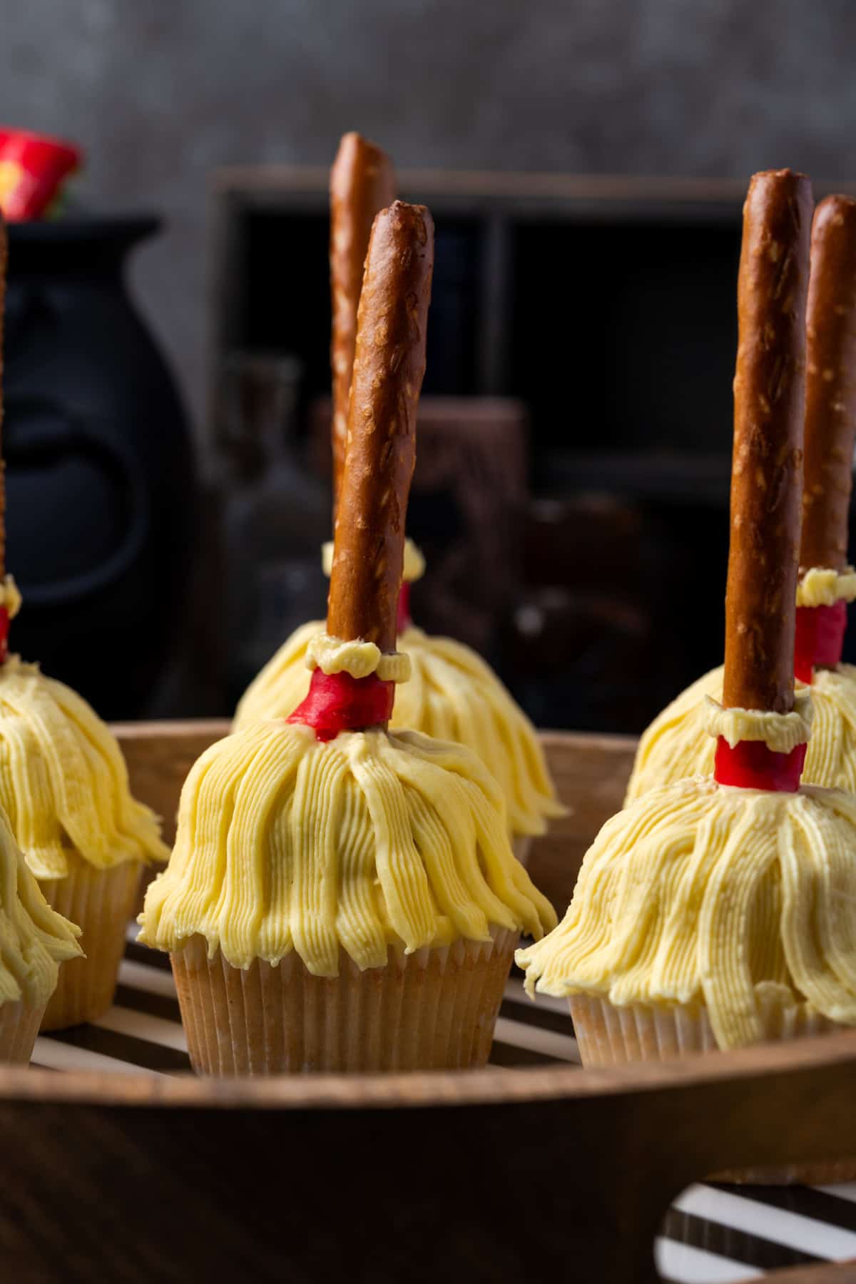 Side view of witch's broom cupcakes on wooden tray.