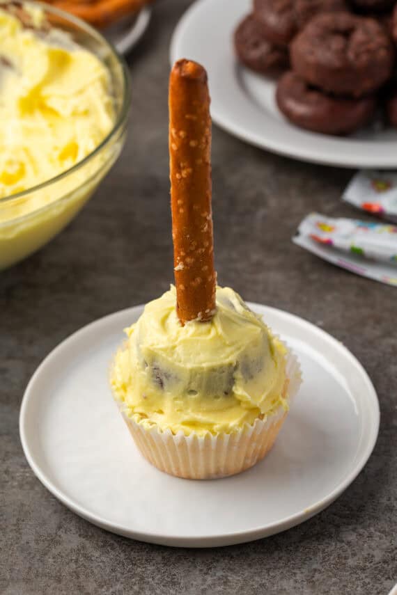 Top a cupcake with a mini donut covered in frosting, forming the base for a broomstick shape.