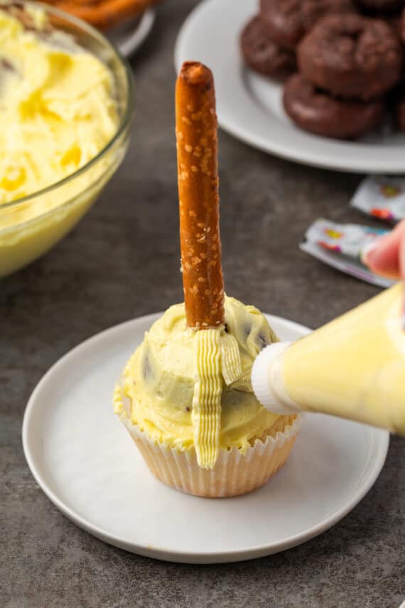 A piping bag with a basket-weave tip piped a mini donut on top of a cupcake.