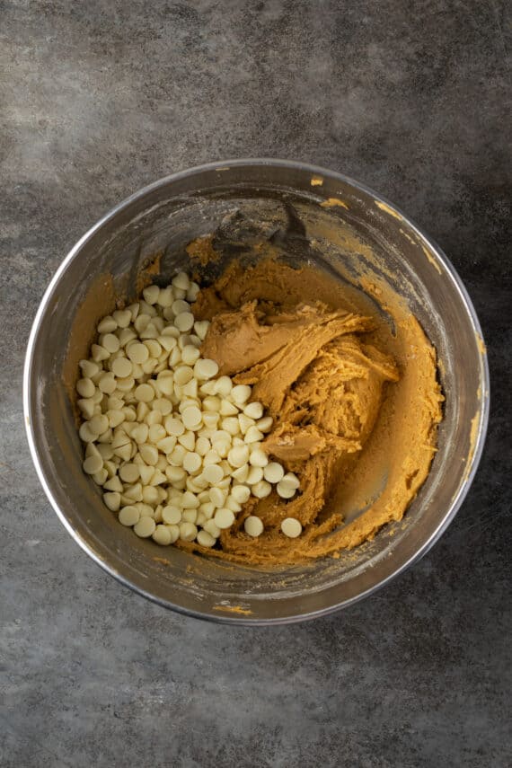 White chocolate added to blondie batter in a metal bowl.