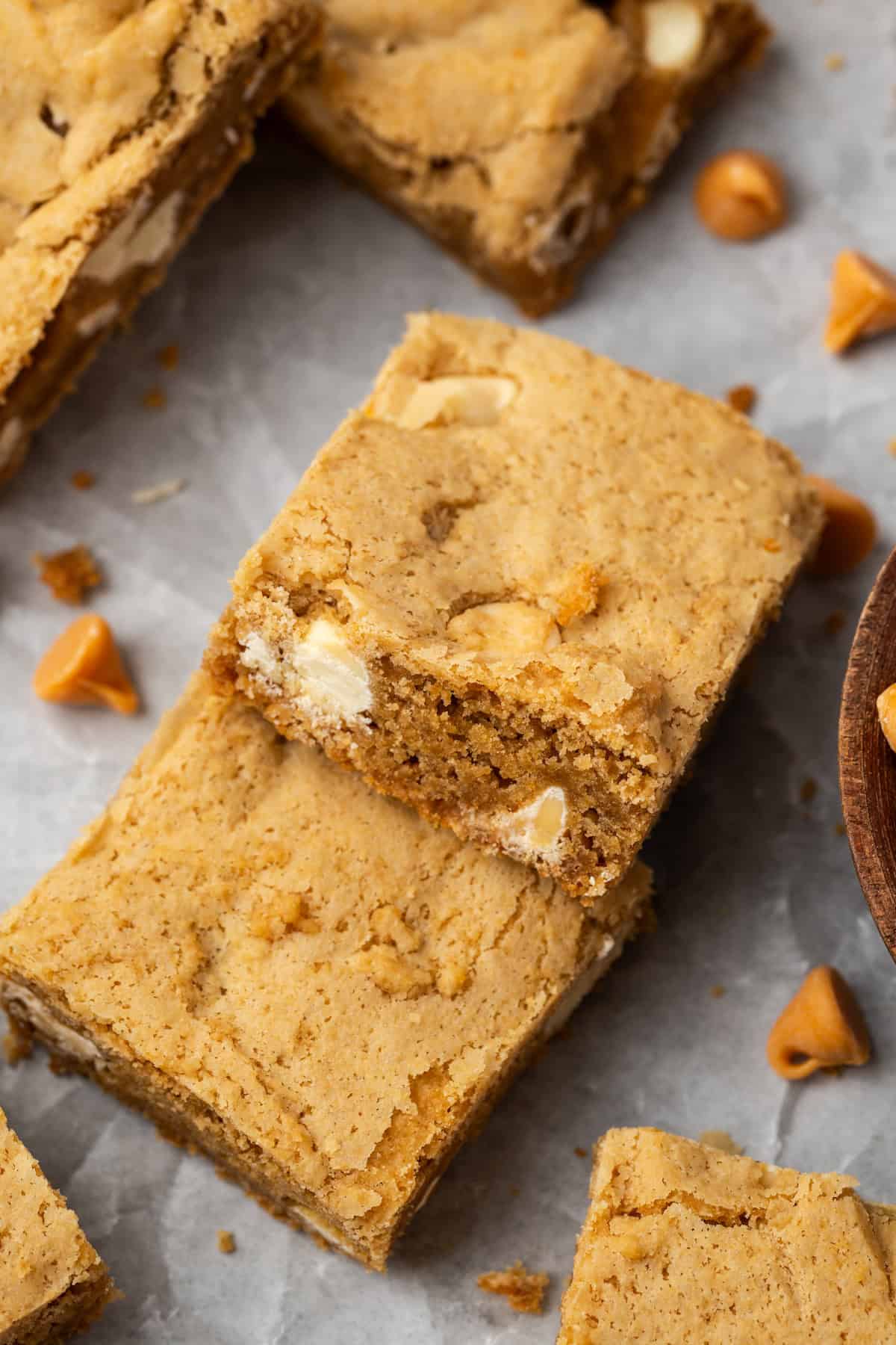Two butterscotch blondies surrounded by more blondies on a piece of parchment paper.