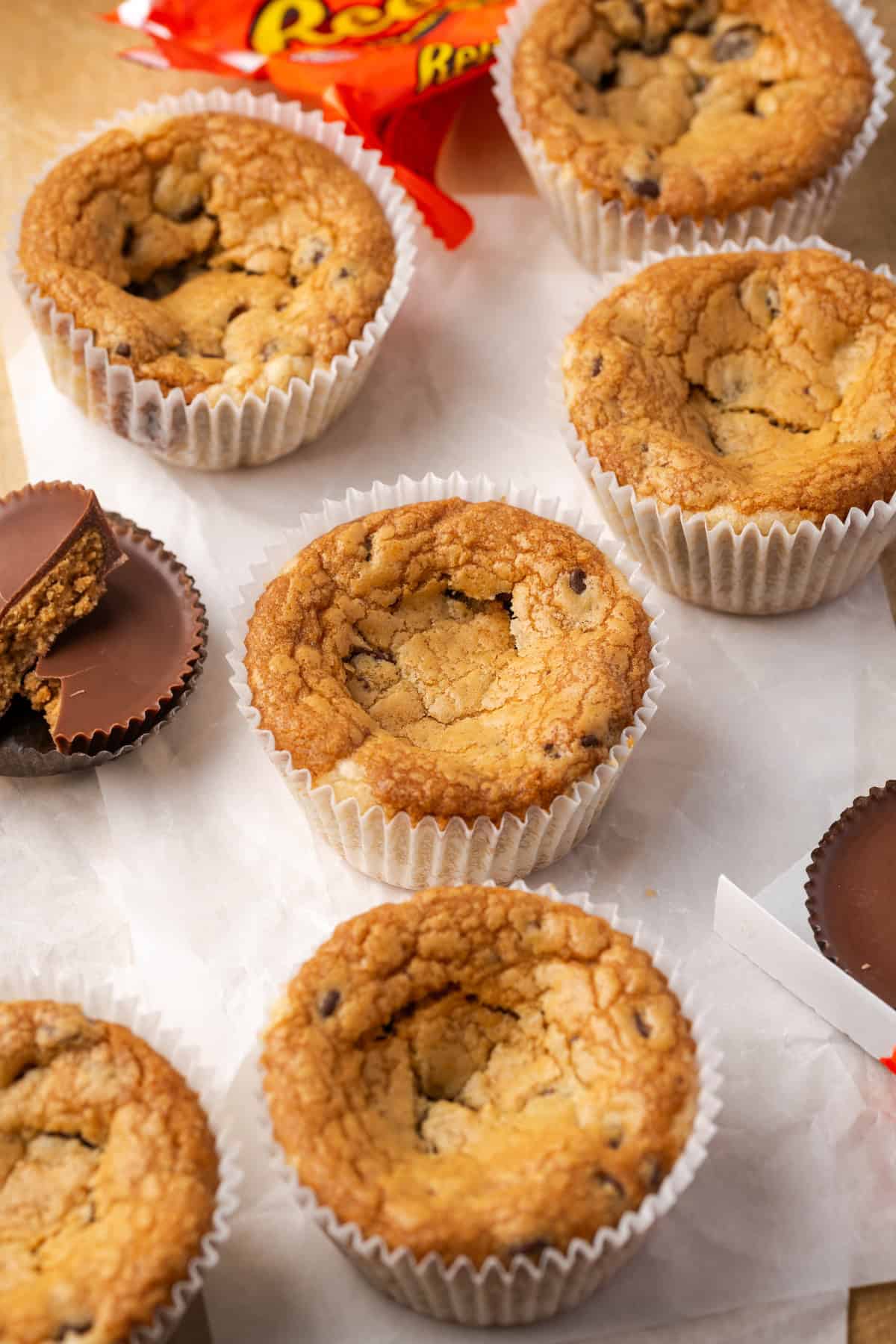 These are the ultimate cookie cups with two types of refrigerated cookie dough baked around a fudgy peanut butter cup. Quick and easy to make! Cookie cups next to partially unwrapped Reese's peanut butter cups.