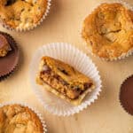 Overhead view of a cookie cup with a bite missing inside a cupcake wrapper, surrounded by more cookie cups.