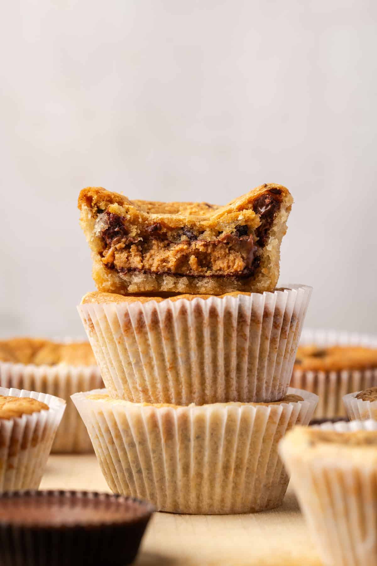 These are the ultimate cookie cups with two types of refrigerated cookie dough baked around a fudgy peanut butter cup. Quick and easy to make! Three cookie cups stacked with a bite missing from the top cookie cup.
