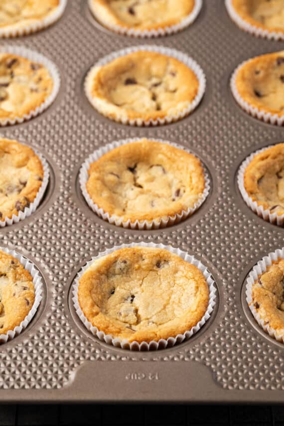 These are the ultimate cookie cups with two types of refrigerated cookie dough baked around a fudgy peanut butter cup. Quick and easy to make! Baked cookie cups inside a muffin tin.