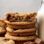 Close up of a stack of extra-thick Milky Way cookies next to a jug of milk.