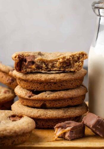 Close up of a stack of extra-thick Milky Way cookies next to a jug of milk.