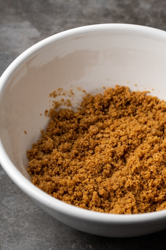 Crushed graham cracker crumbs combined with butter and sugar in a bowl.