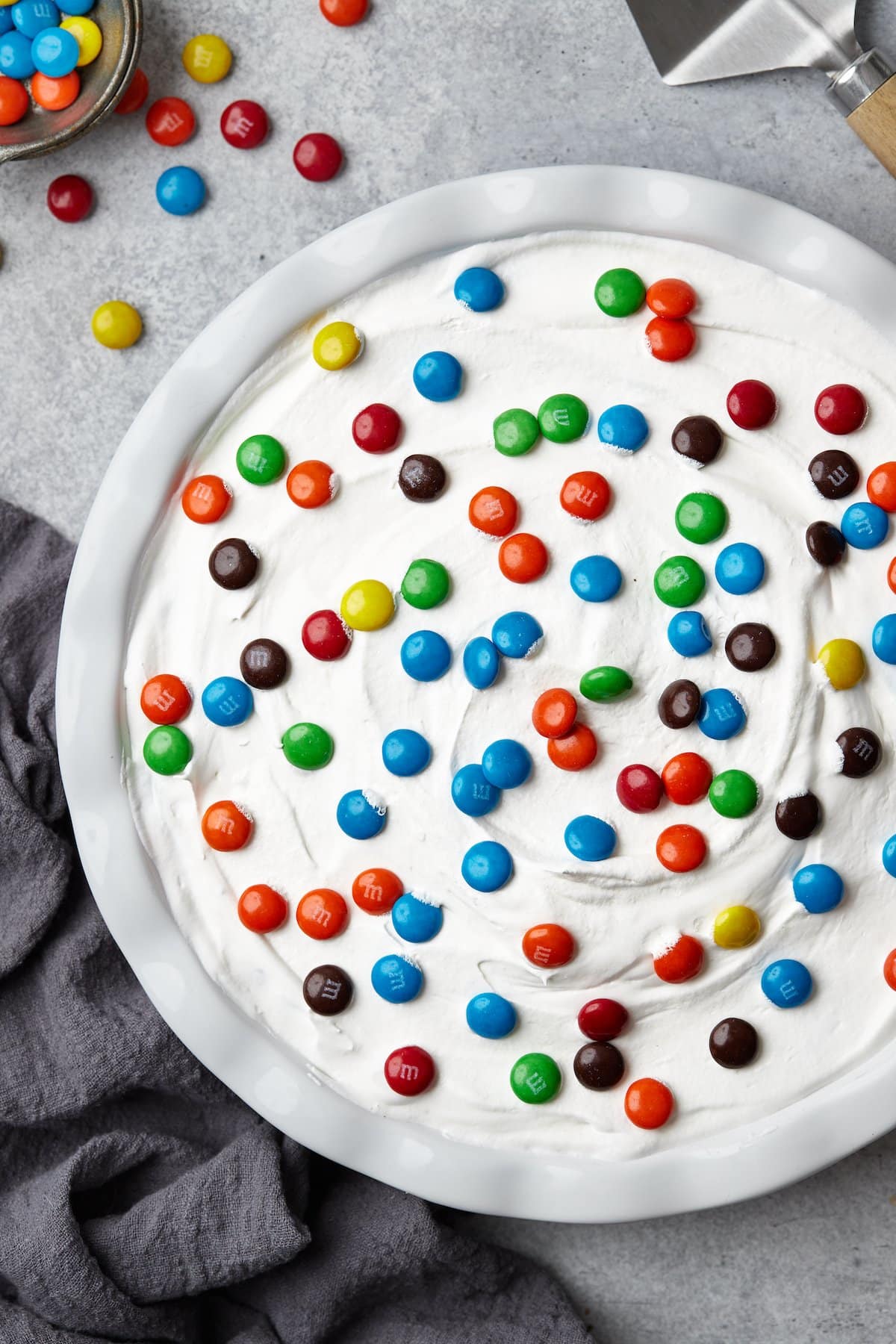 Top view of a whole candy pie topped with whipped cream and M&Ms.
