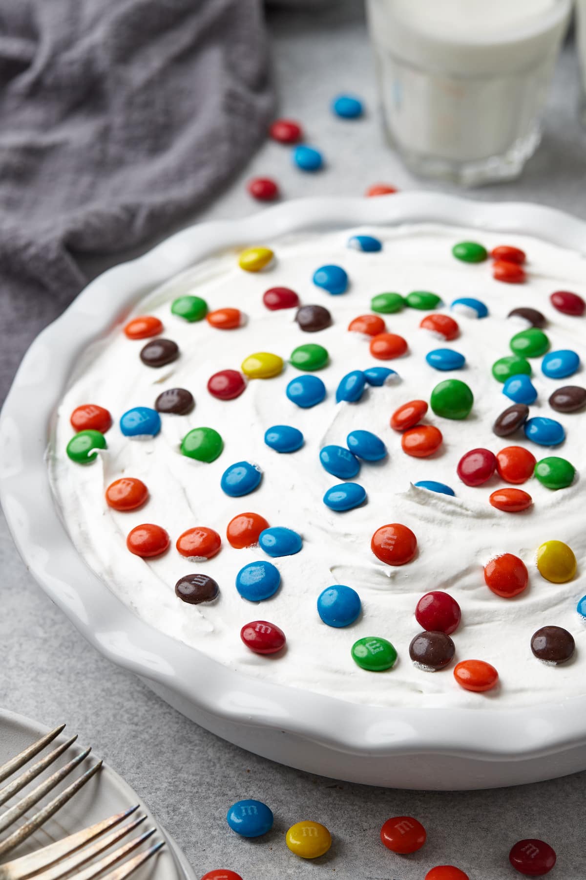 A whole candy pie topped with whipped cream and M&Ms.