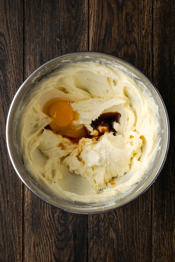 Egg and vanilla added to creamed butter and sugar in a mixing bowl.