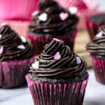 Chocolate cupcakes frosted with a rich and decadent chocolate fudge buttercream frosting, topped with sprinkles.