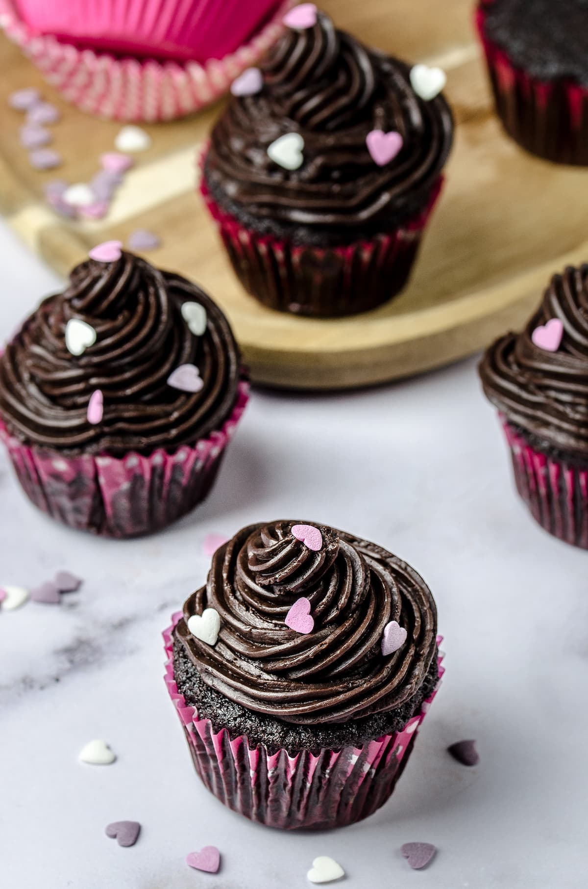 Chocolate cupcakes frosted with a rich and decadent chocolate fudge buttercream frosting, topped with sprinkles.