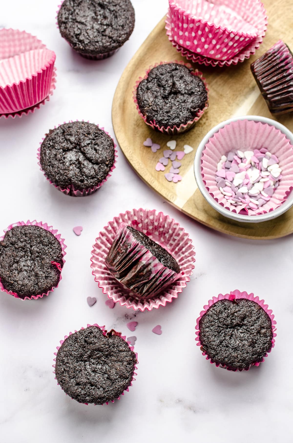 Dark chocolate cupcakes waiting to be frosted and decorated with sprinkles.