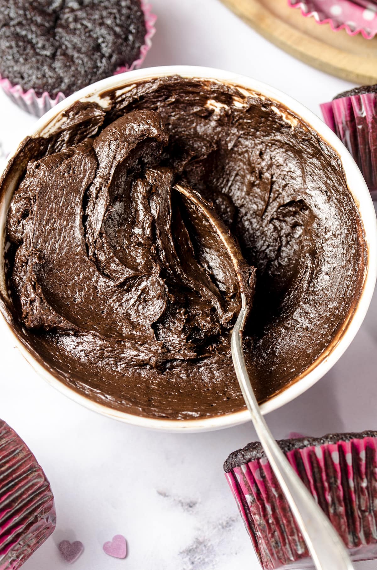 A mixing bowl of dark chocolate cake batter with a spoon.