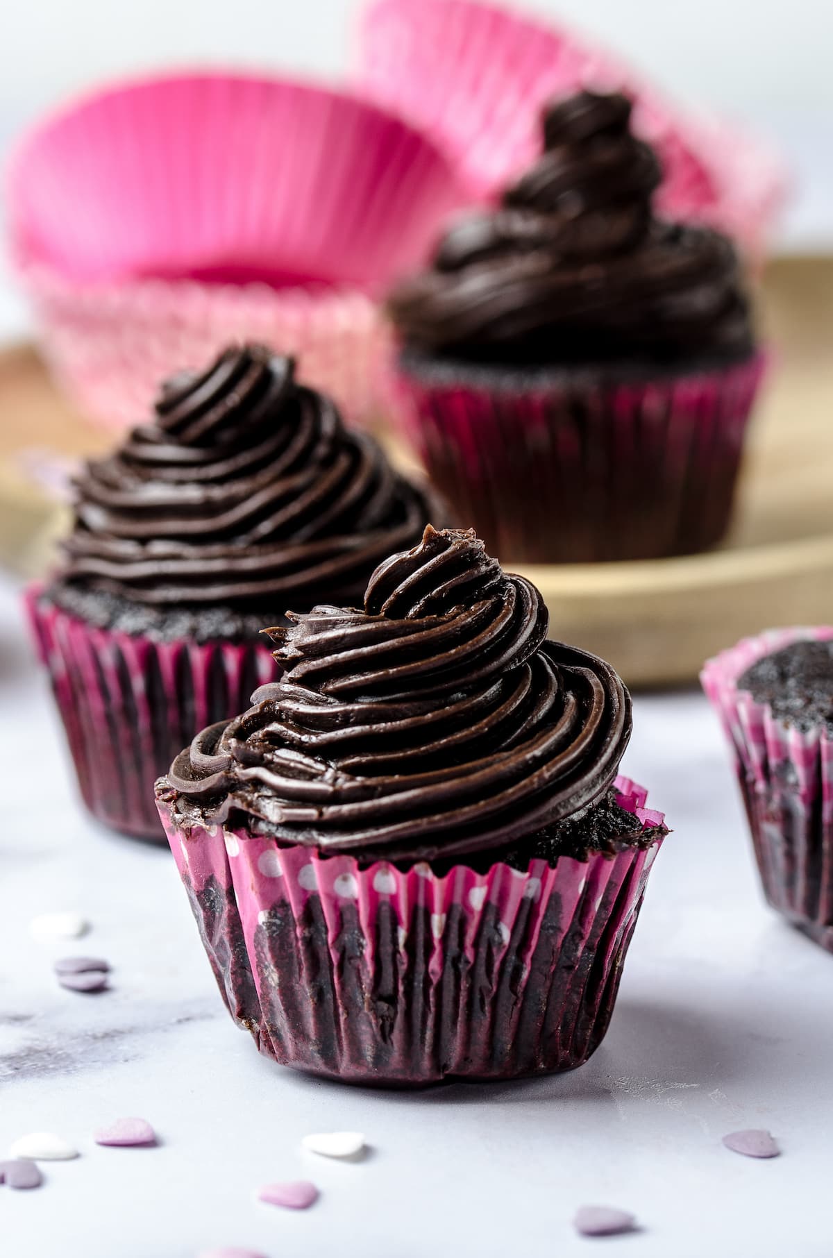 Chocolate cupcakes topped with dark chocolate buttercream frosting swirls.