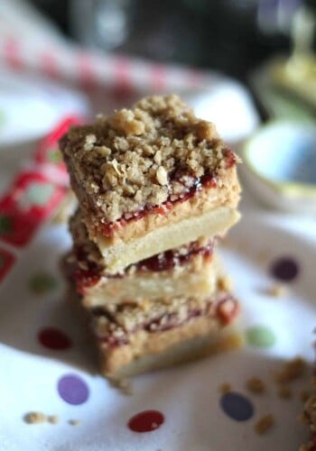 Three peanut butter jelly bars stacked on top of a polka dot table cloth.