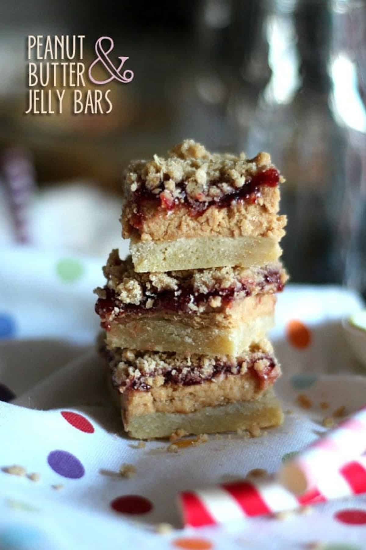 Three peanut butter jelly bars stacked on top of a polka dot table cloth.