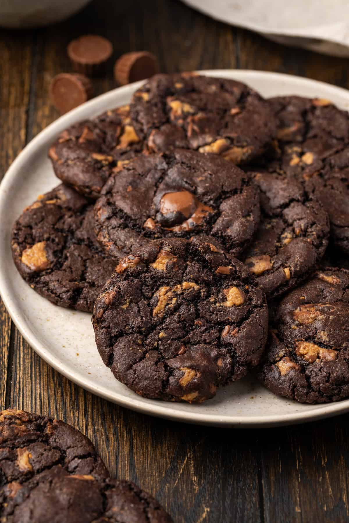 A pile of peanut butter chocolate cookies arranged on a white plate.