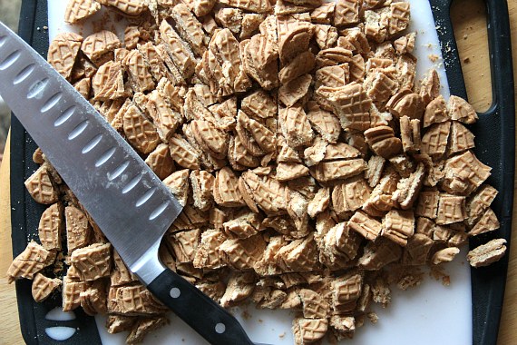 A large knife lays on top of chopped Nutter Butter cookies on a cutting board.