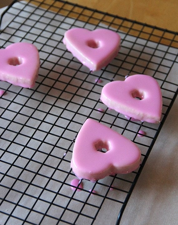 Pink-glazed Valentine's cookies on a wire rack.