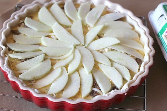 Apple cheddar cheese quiche in a red pie plate.