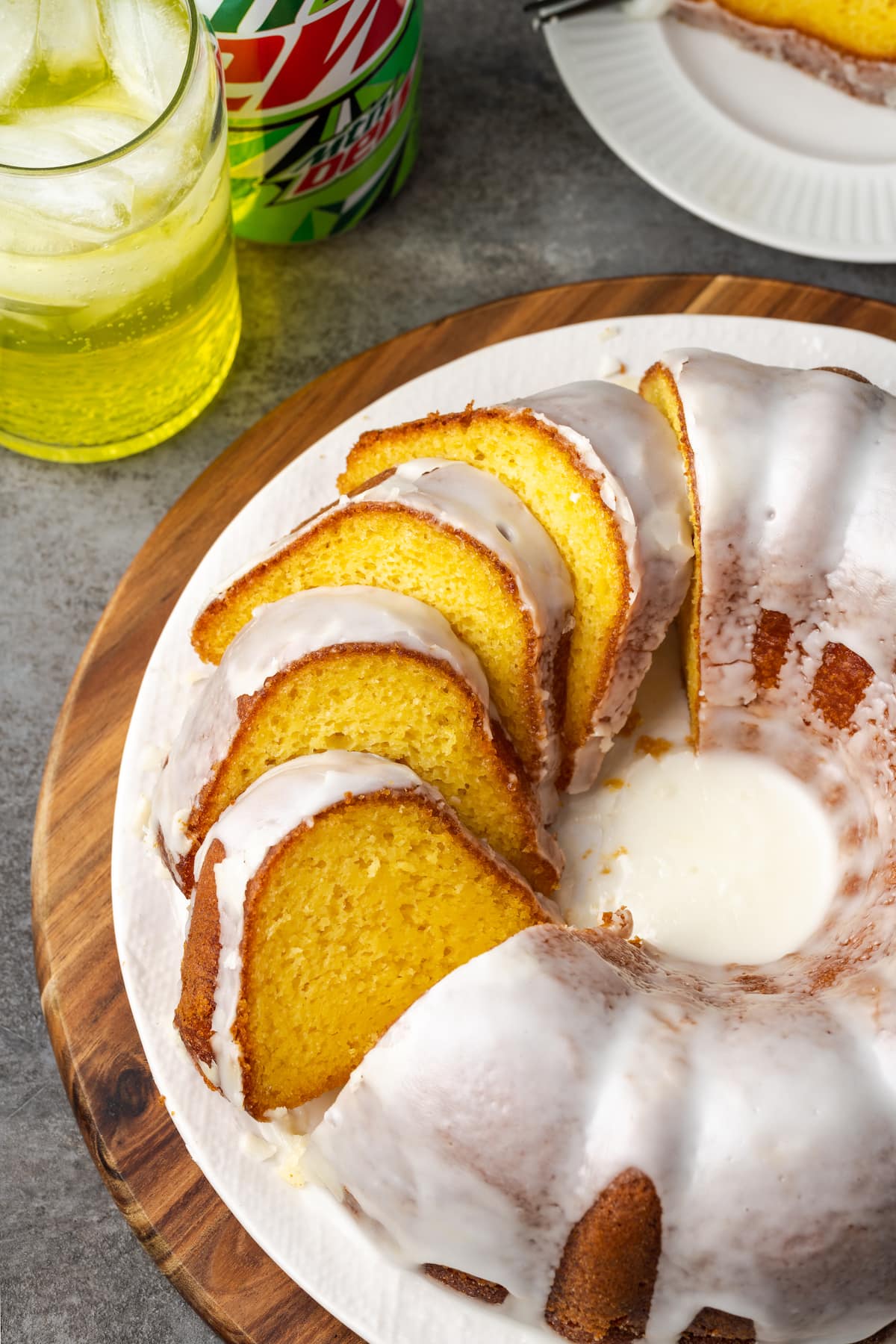 Mountain Dew bundt cake with sliced ​​glaze on a plate next to a glass of Mountain Dew.