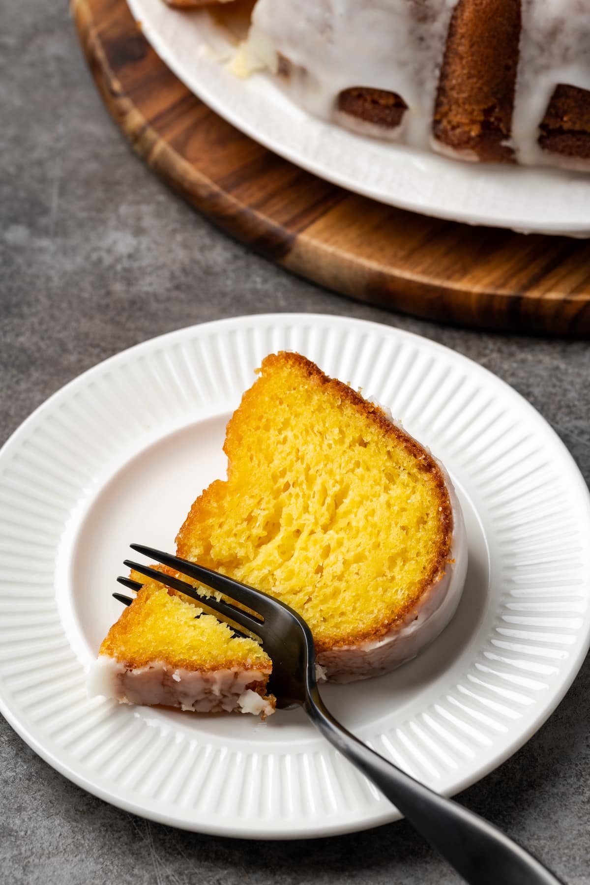 A slice of Mountain Dew cake on a white plate with a fork stuck into the corner.