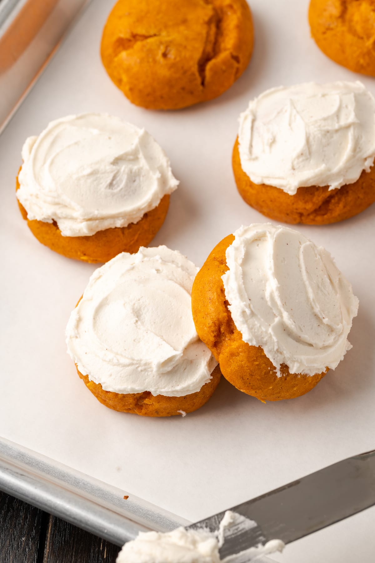 Assorted frosted cake mix pumpkin cookies on a baking sheet.