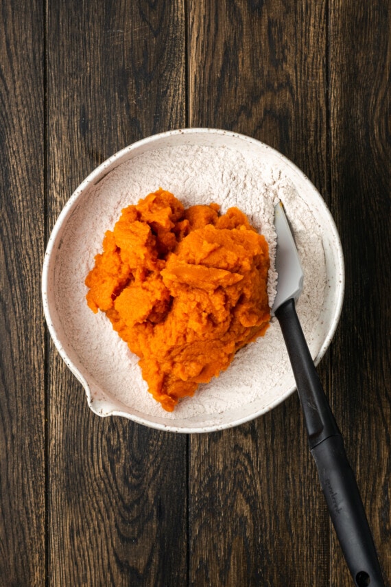 Canned pumpkin added to a mixing bowl with spice cake mix.