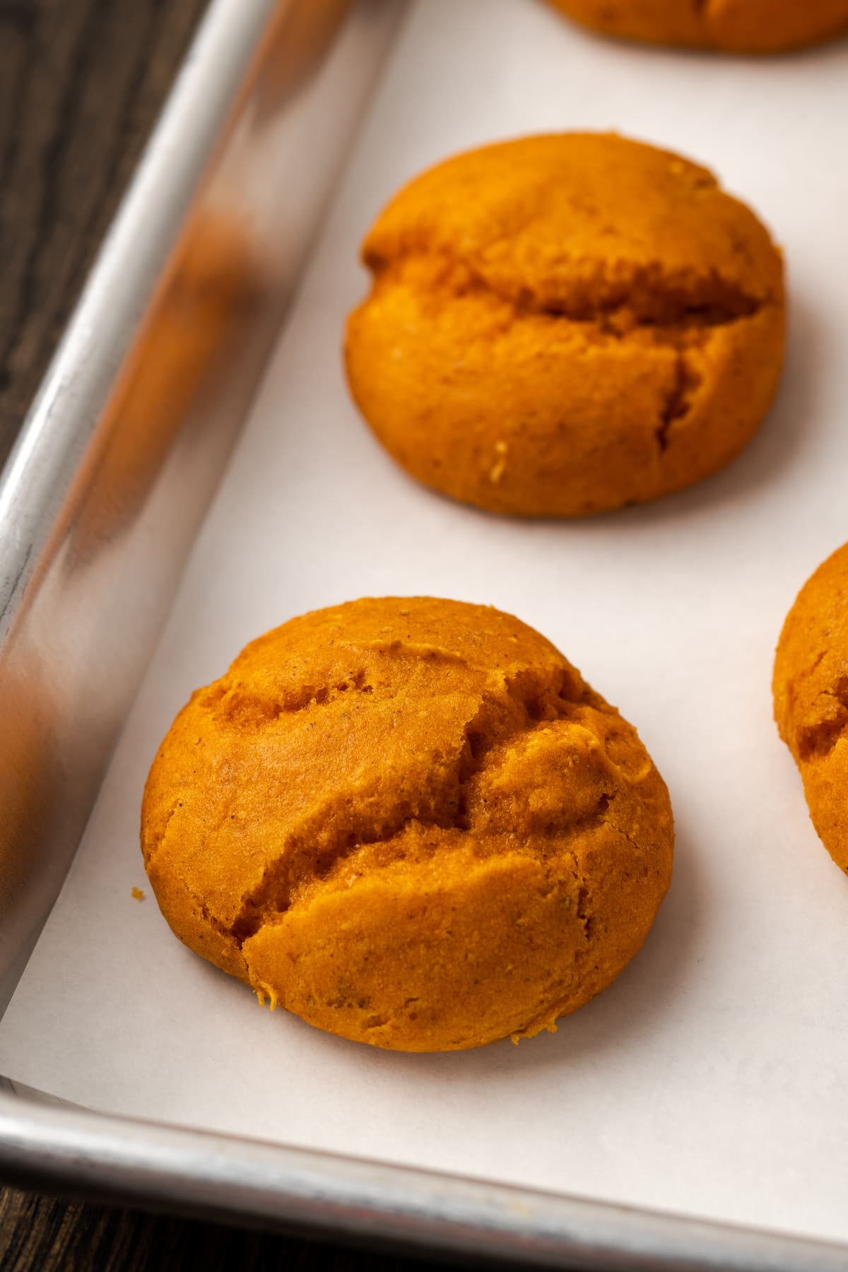 Close up of baked cake mix pumpkin cookies on a metal baking sheet.