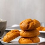 Three cake mix pumpkin cookies stacked on a plate, with a fourth cookie leaning against the stack.