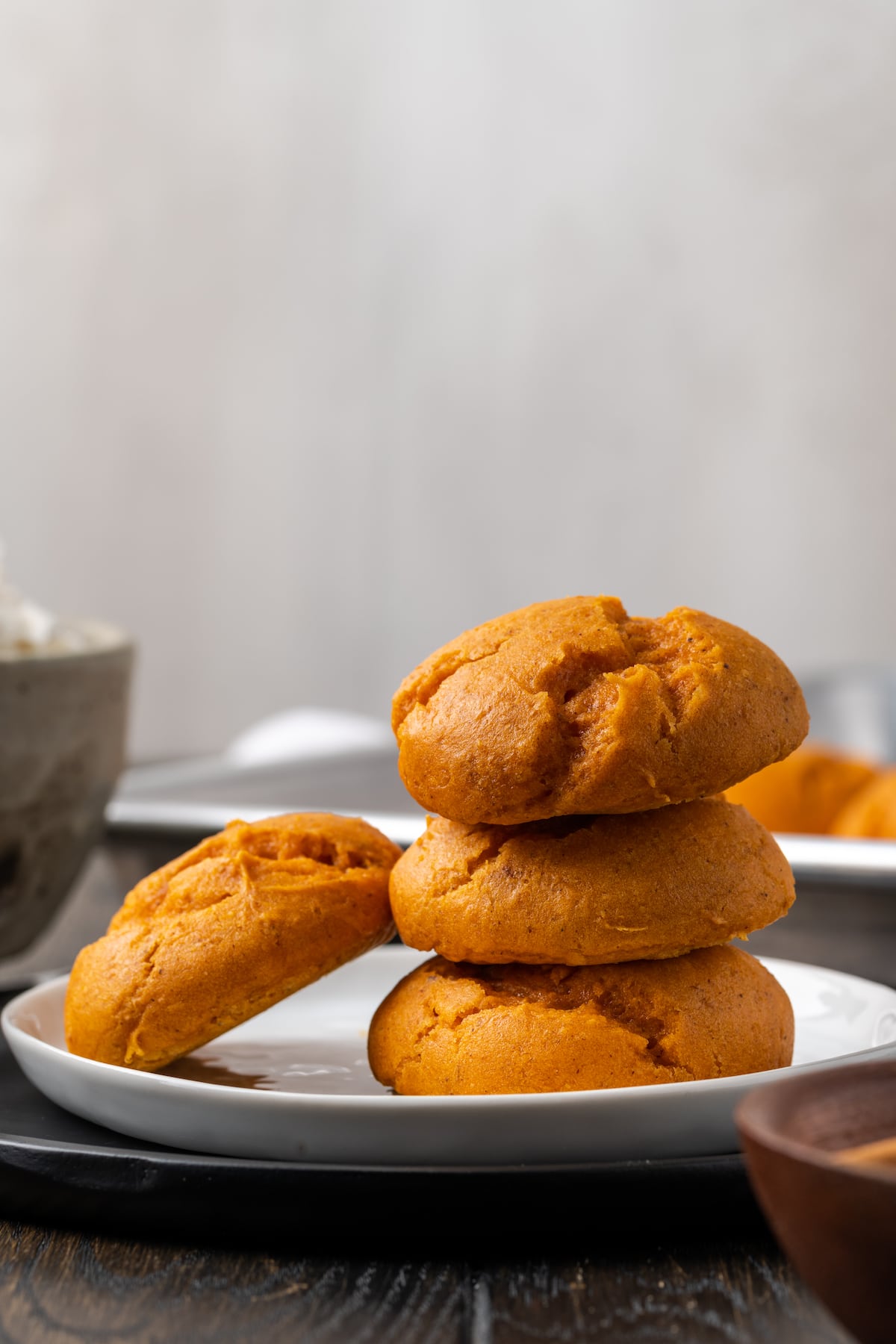 Three cake mix pumpkin cookies stacked on a plate, with a fourth cookie leaning against the stack.