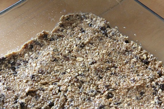 Homemade snack bar mixture is spread over a baking sheet.