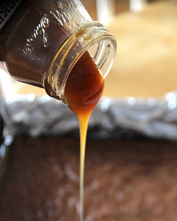 pouring caramel on top of brownies