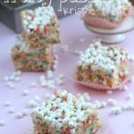 Double marshmallow Fruity Pebbles Krispie Treats surrounded by scattered marshmallows.