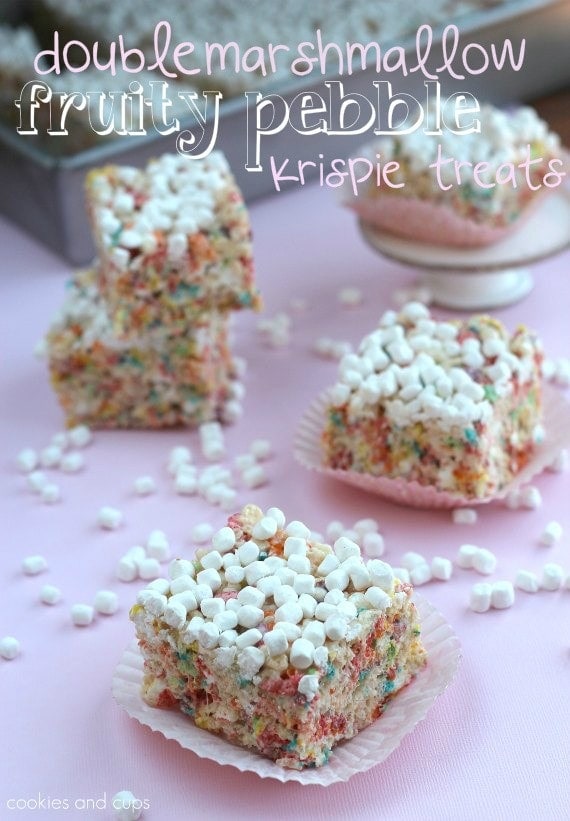 Double marshmallow Fruity Pebbles Krispie Treats surrounded by scattered marshmallows.
