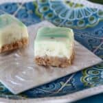 Two key lime fudge bars on a square white plate.