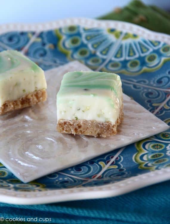 Two key lime fudge bars on a square white plate.